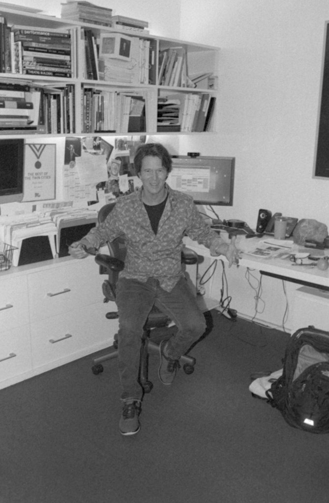 Two adults sit on a pink carpet and talk.
