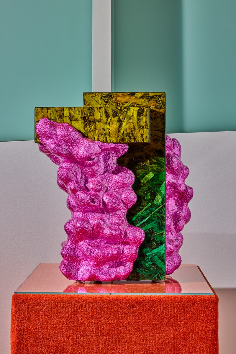 A colorful end table sits on an orange pedistal.