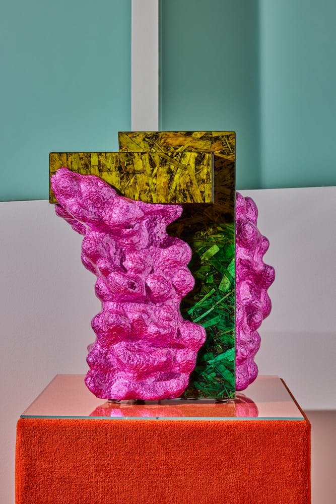 A colorful end table sits on an orange pedistal.